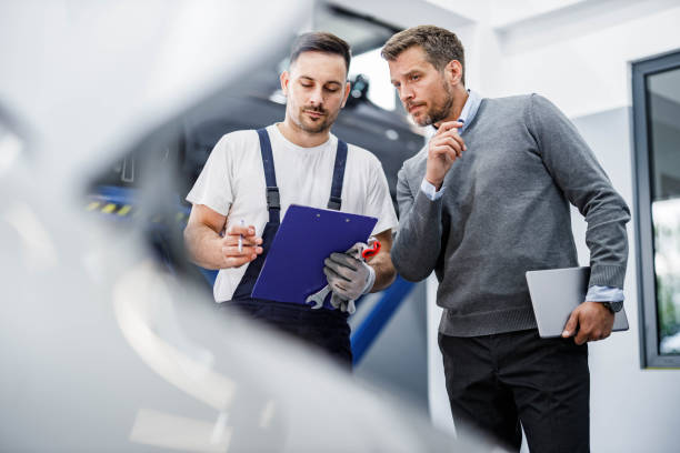 Young mechanic and his manager going through paperwork in auto repair shop