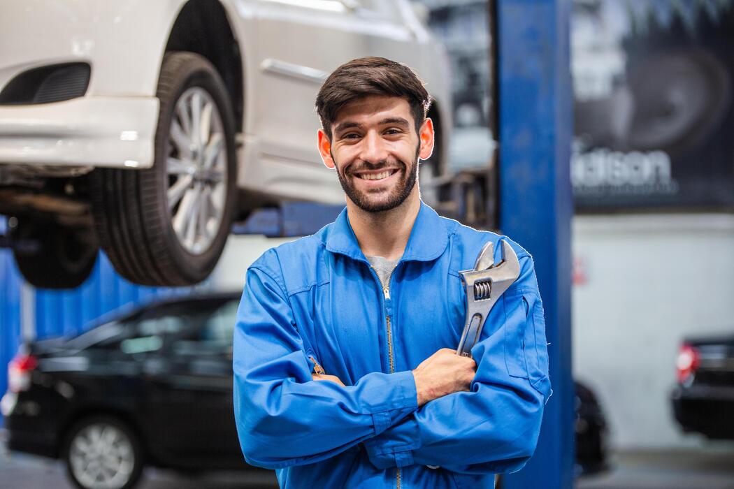 portrait-of-smiling-male-mechanic-technician-holding-wrench-in-arms-crossed-at-auto-garage-repair-and-maintenance-career-after-service-checking-car-damage-broken-part-free-photo